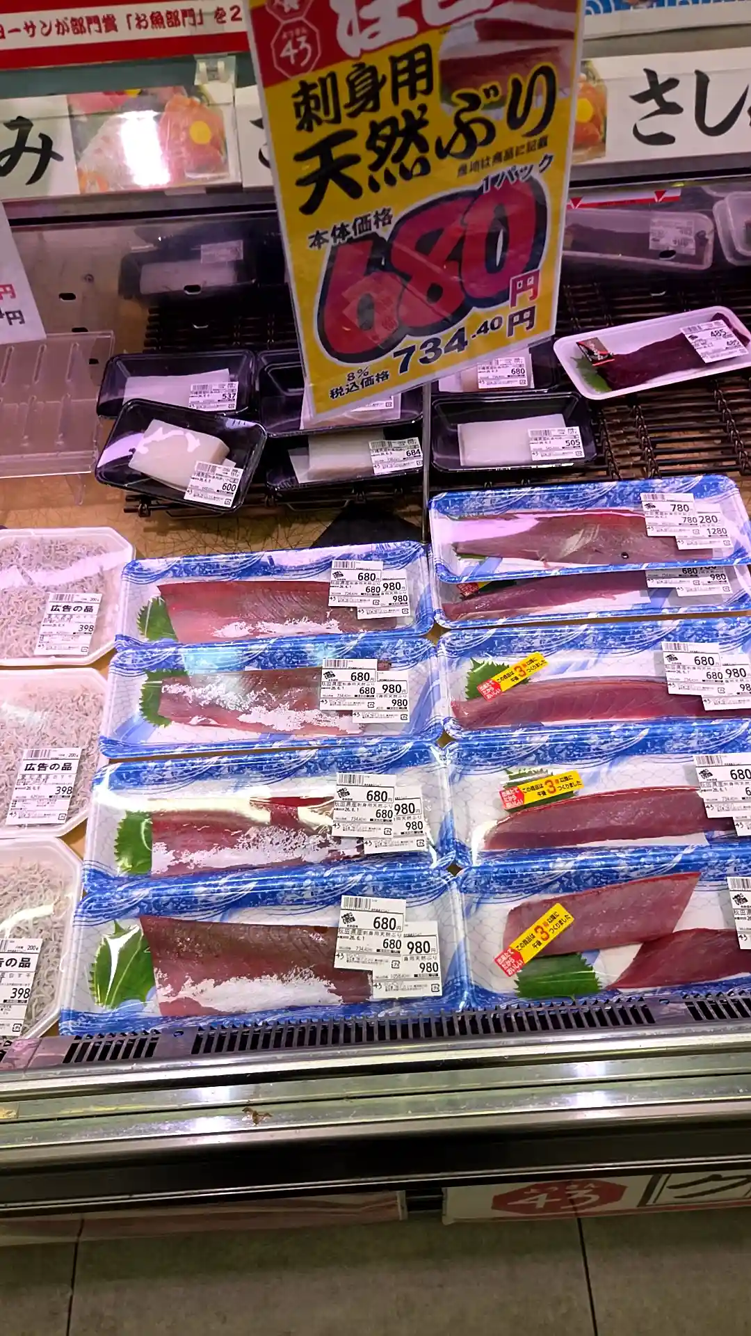 横浜の安いスーパー・ビッグヨーサンの鮮魚売り場。「刺身用 天然ぶり1パック 本体価格680円（税込734円）」の黄色いPOPの下に、天然ぶりの柵が680〜980円、広告の品のしらすが398円で並ぶ