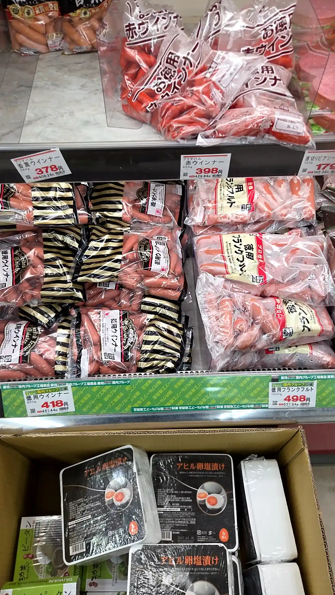 業務スーパーのソーセージ売り場。徳用ウインナー800gが418円、徳用フランクフルト1000gが498円、香薫ウインナー378円など大容量・激安で並んでいる