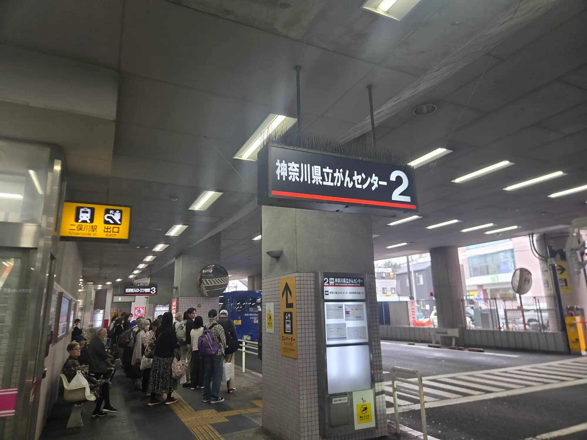 二俣川駅のバスターミナル。駅ビルの下に乗り場が並び、行き先表示と駅出口の案内がある