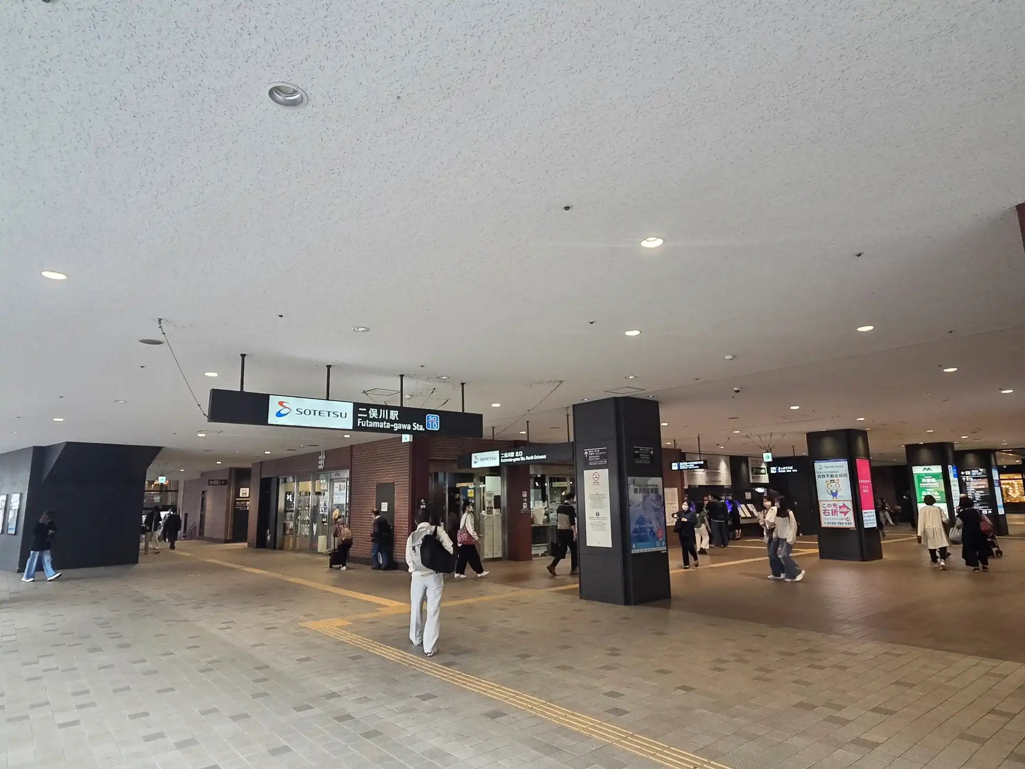 相鉄線二俣川駅(駅番号SO10)のコンコース。北口改札前の広い通路に駅名標と案内表示があり、通勤・買い物客が行き交う平日の様子