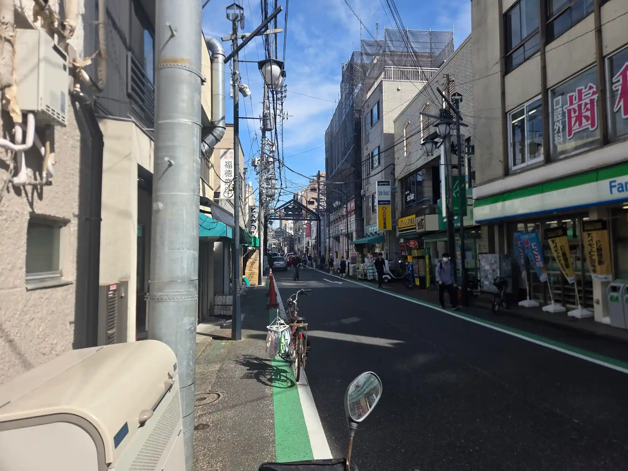 白楽駅から続く六角橋商店街の通り。コンビニや個人商店、クリニックが並び、奥に商店街のアーチが見える