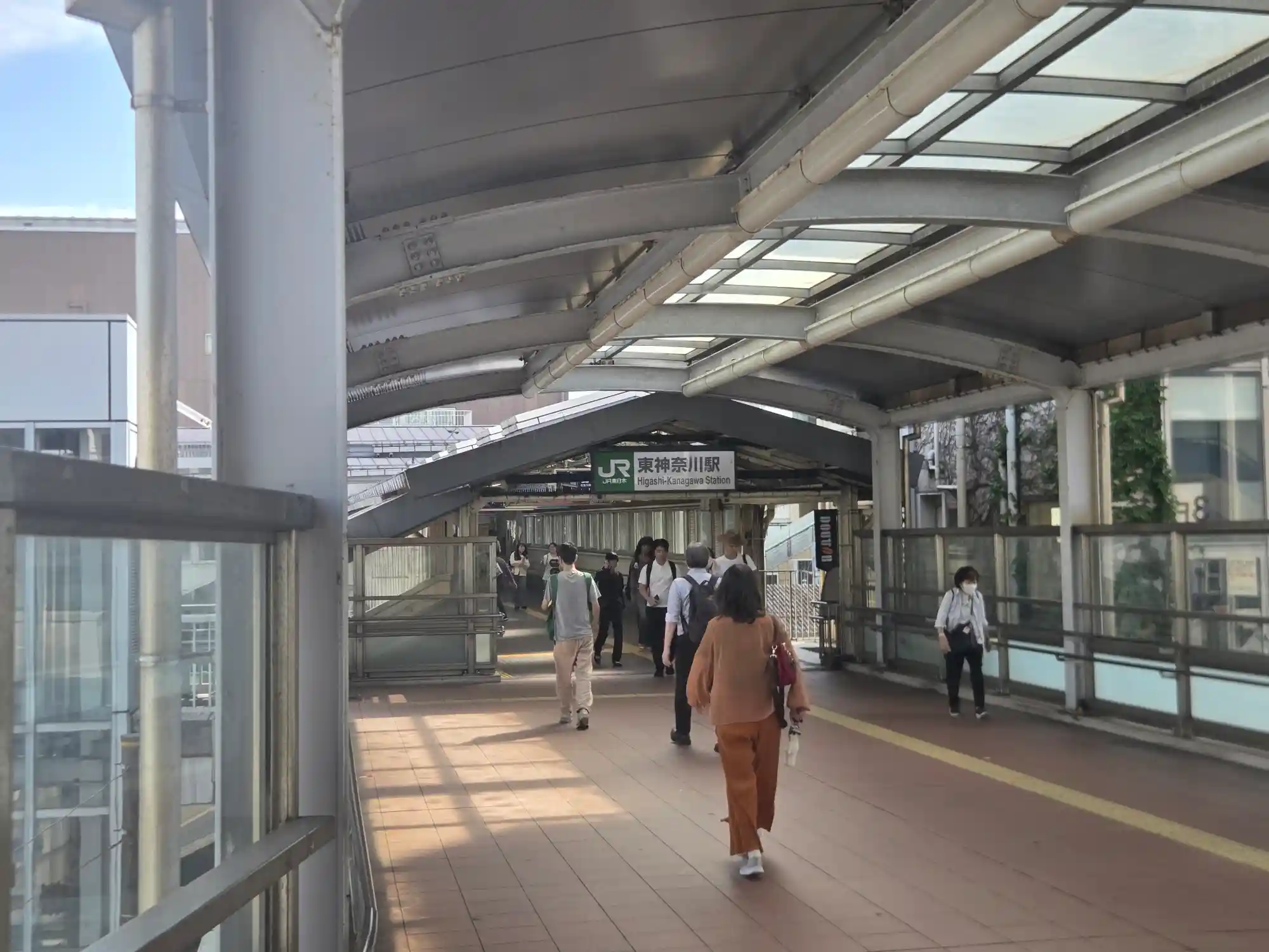 JR東神奈川駅の改札へ続く屋根付き通路を人が行き交う様子。横浜駅まで京浜東北・根岸線で3分の駅
