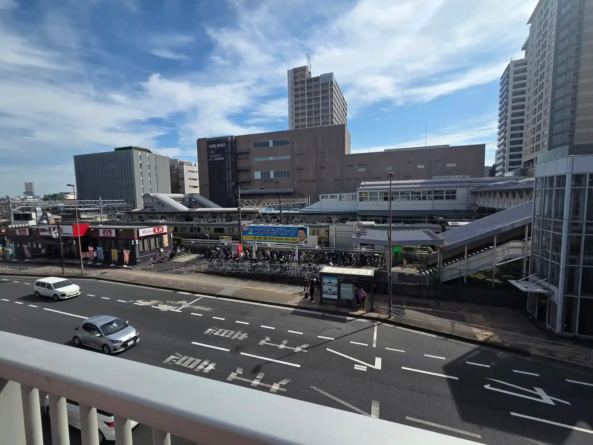 歩道橋から見たJR東神奈川駅と駅ビル。手前に片側2車線の幹線道路と駐輪場があり、線路と道路が密集している
