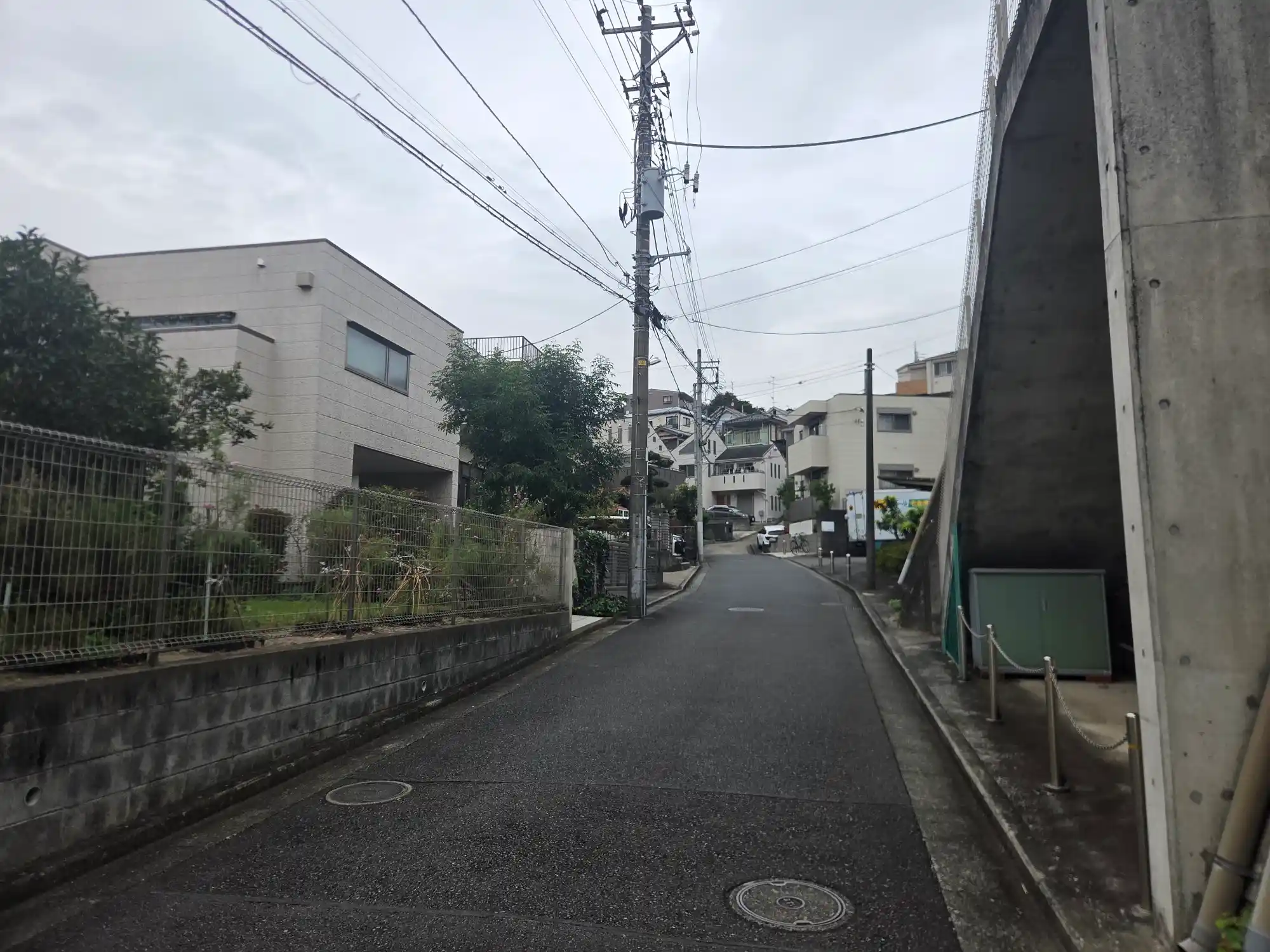 二俣川駅周辺の住宅街に続く上り坂。擁壁の横を丘の上の戸建てやアパートへ向かって道が登っていく