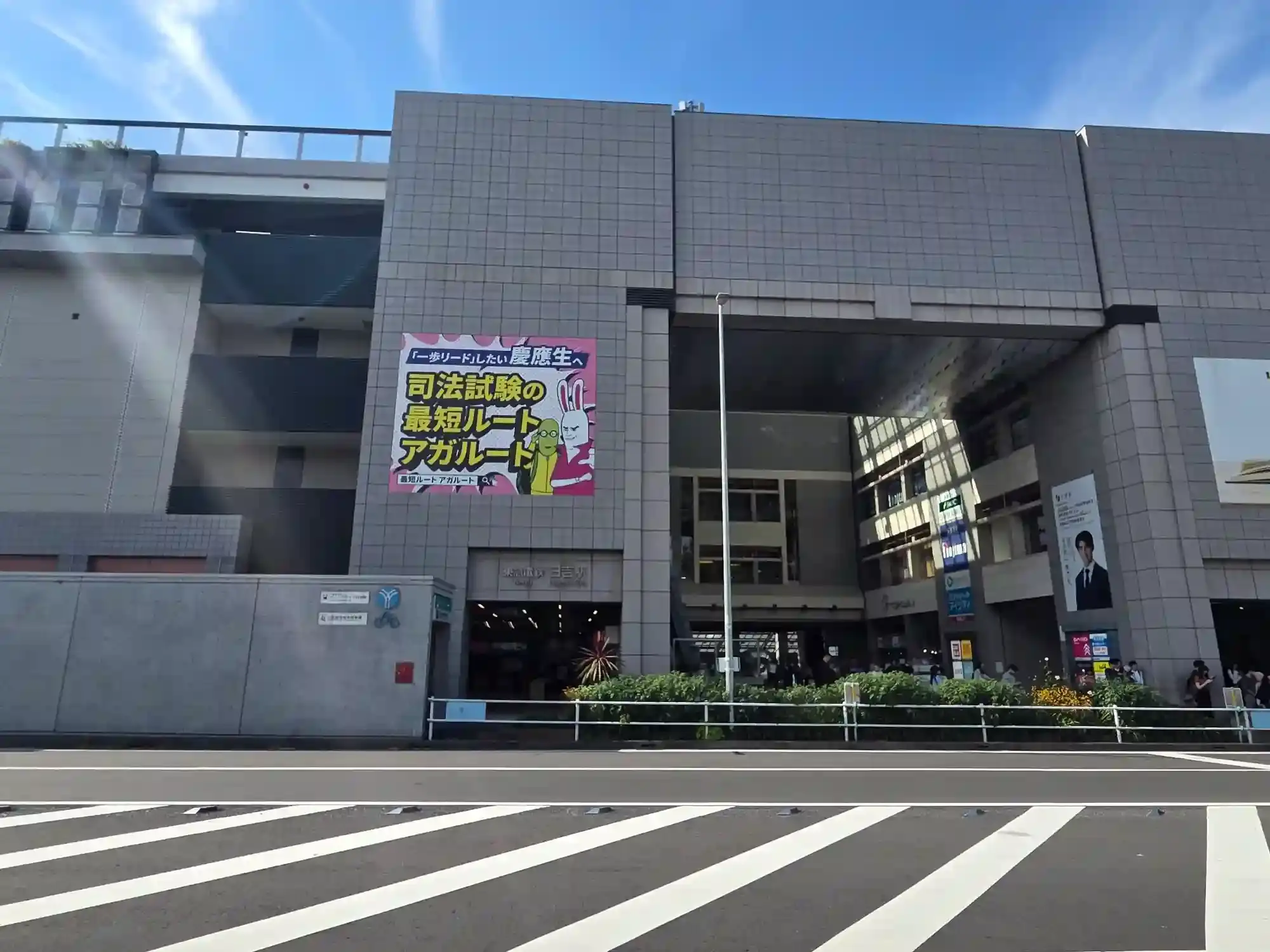 東急日吉駅の入口と駅ビル。慶應生に向けた広告が掲げられ、学生街であることがわかる日吉駅前