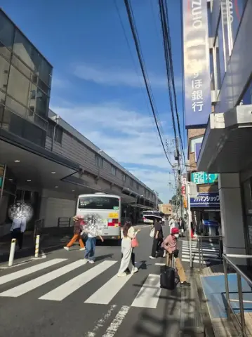 綱島駅前の高架沿いを走るバスと横断歩道を渡る人