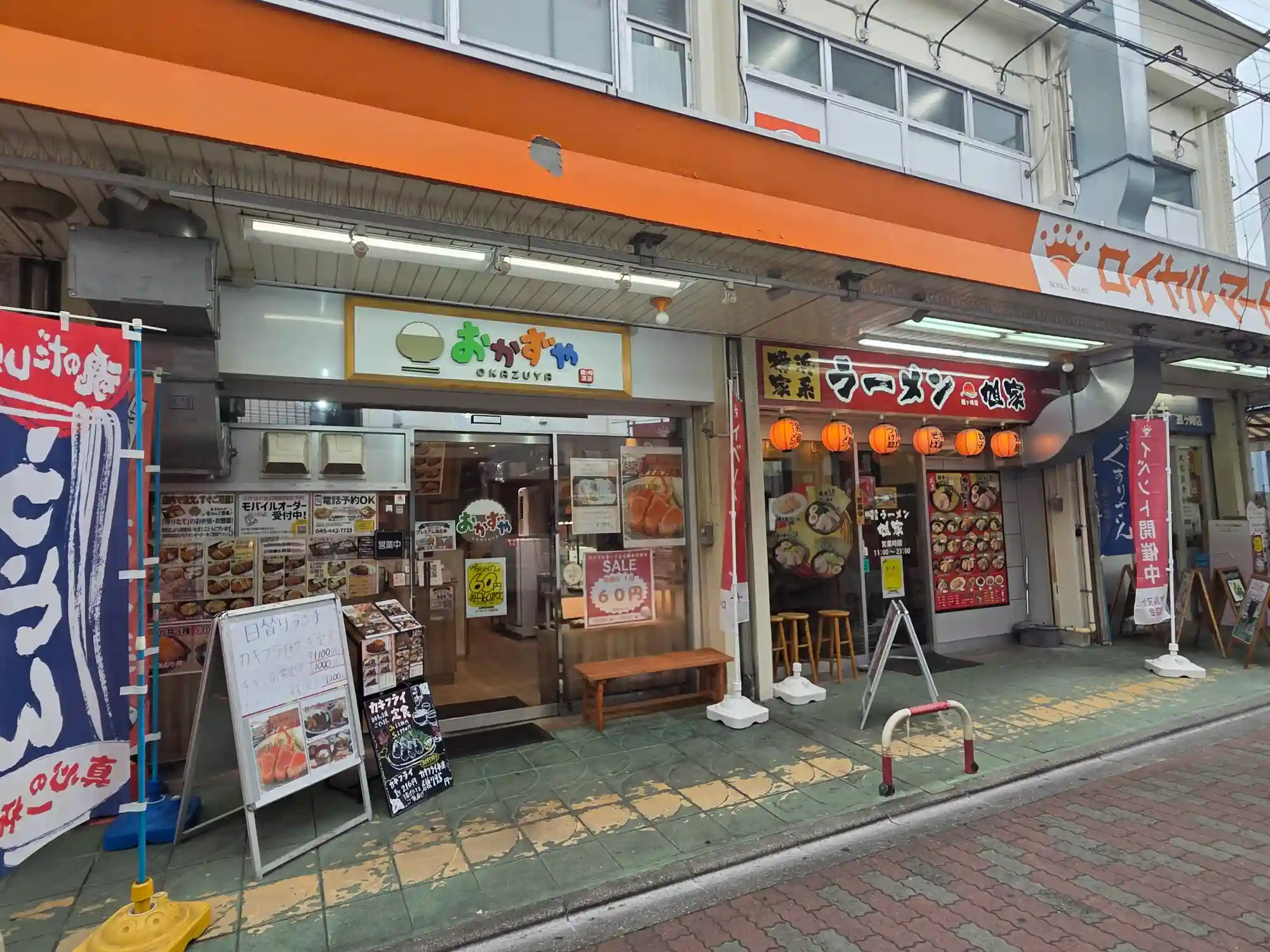 鶴ケ峰商店街に並ぶ定食店と家系ラーメン店の店先