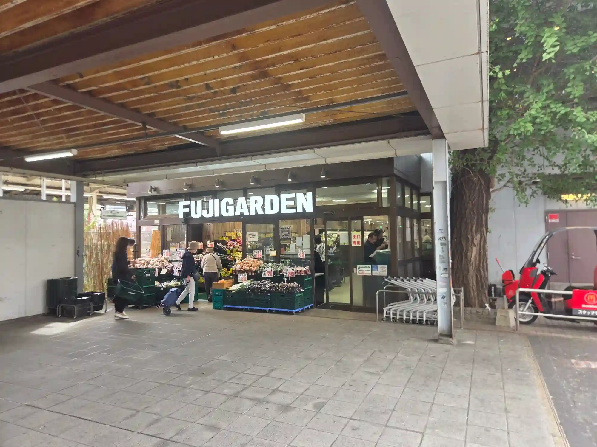 保土ヶ谷駅に隣接するスーパー「FUJIGARDEN」の入口。店頭に野菜や果物が並び、買い物客が出入りしている