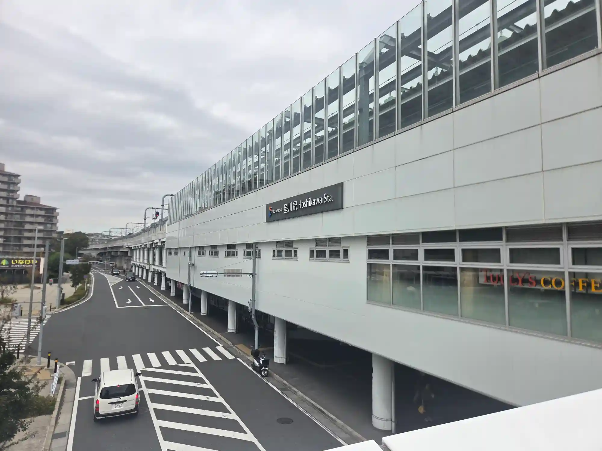 高架化された相鉄線星川駅の外観。高架下にタリーズコーヒーが入り、駅前の道路は広く整備されている