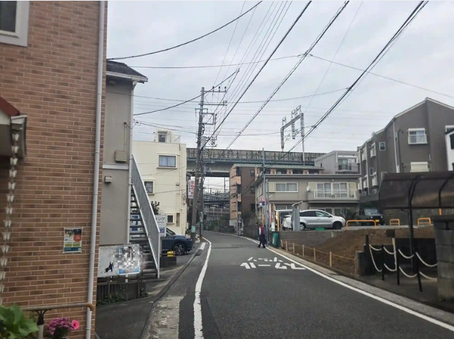 西谷駅近くの住宅街の道。低層のアパートや住宅のすぐ奥を鉄道の高架が横切っている