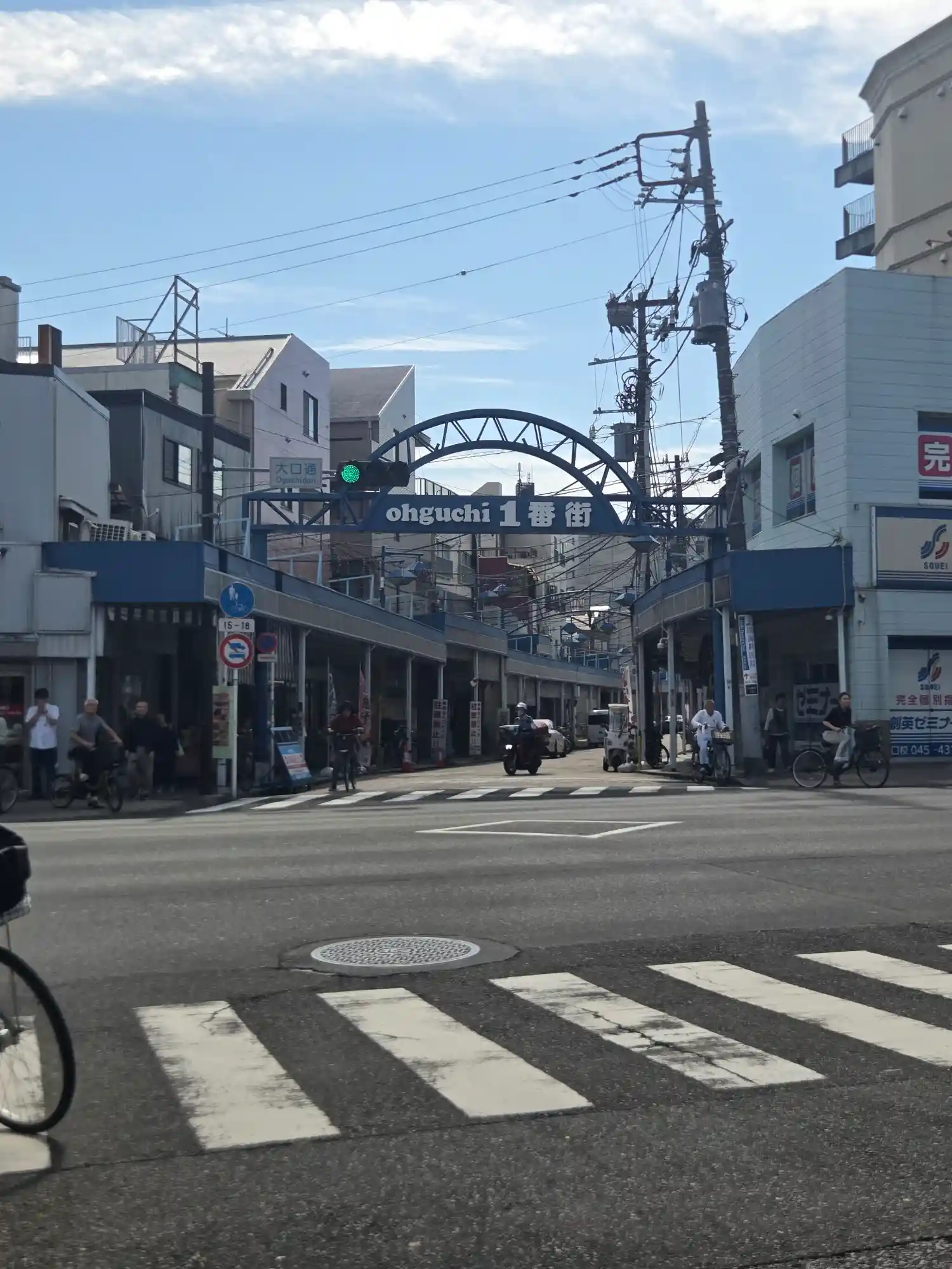大通りの交差点から見た「ohguchi 1番街」のアーチ。自転車に乗った住民が行き交う商店街の入口