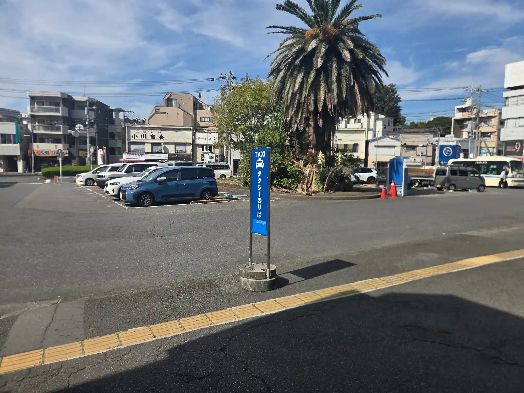 大口駅前のロータリー。ヤシの木の植え込みとタクシー乗り場があり、周りには低層のマンションや商店が並ぶ
