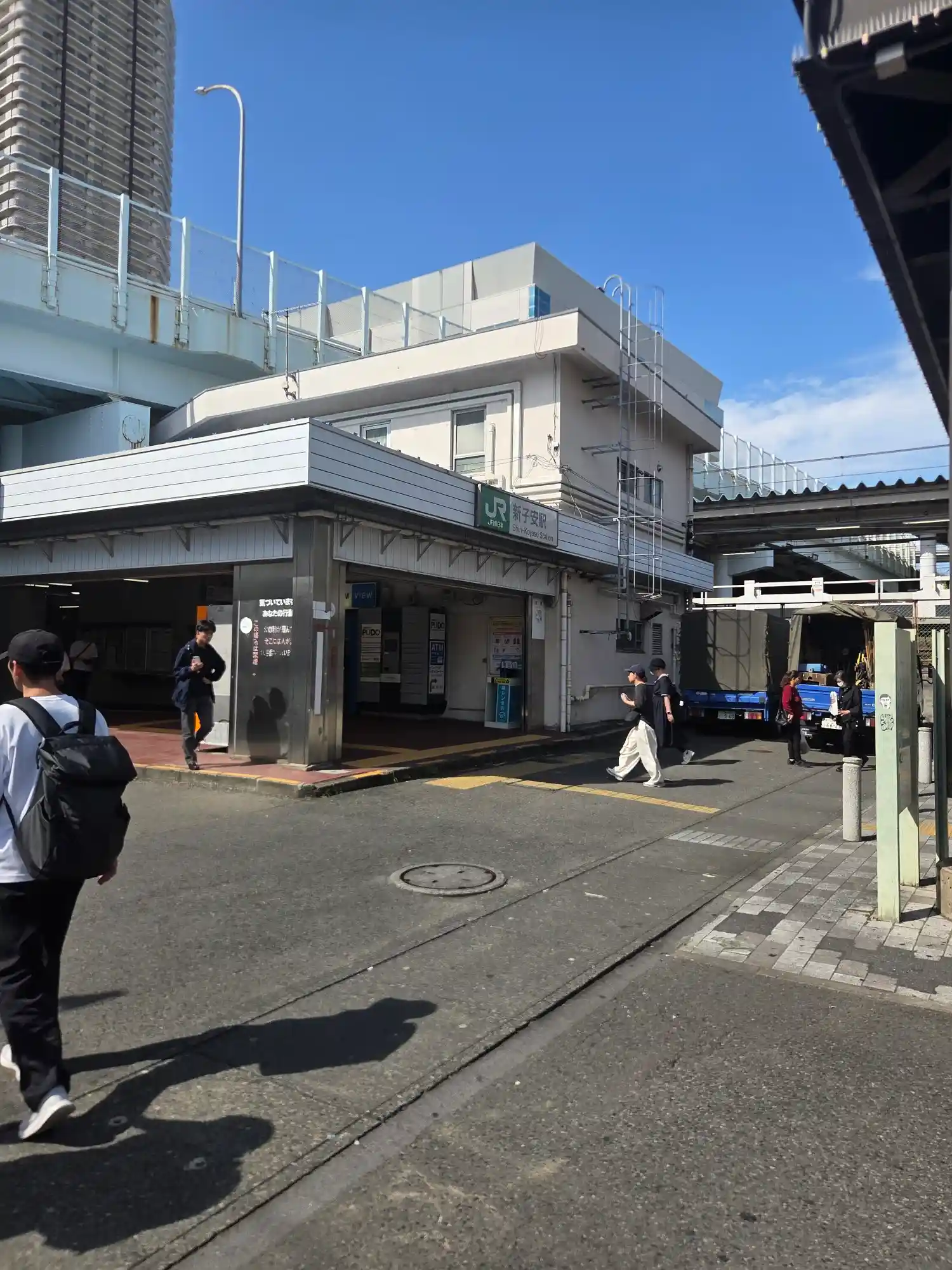JR新子安駅の駅舎と改札前の様子。駅舎の背後には高層タワーマンションが見える