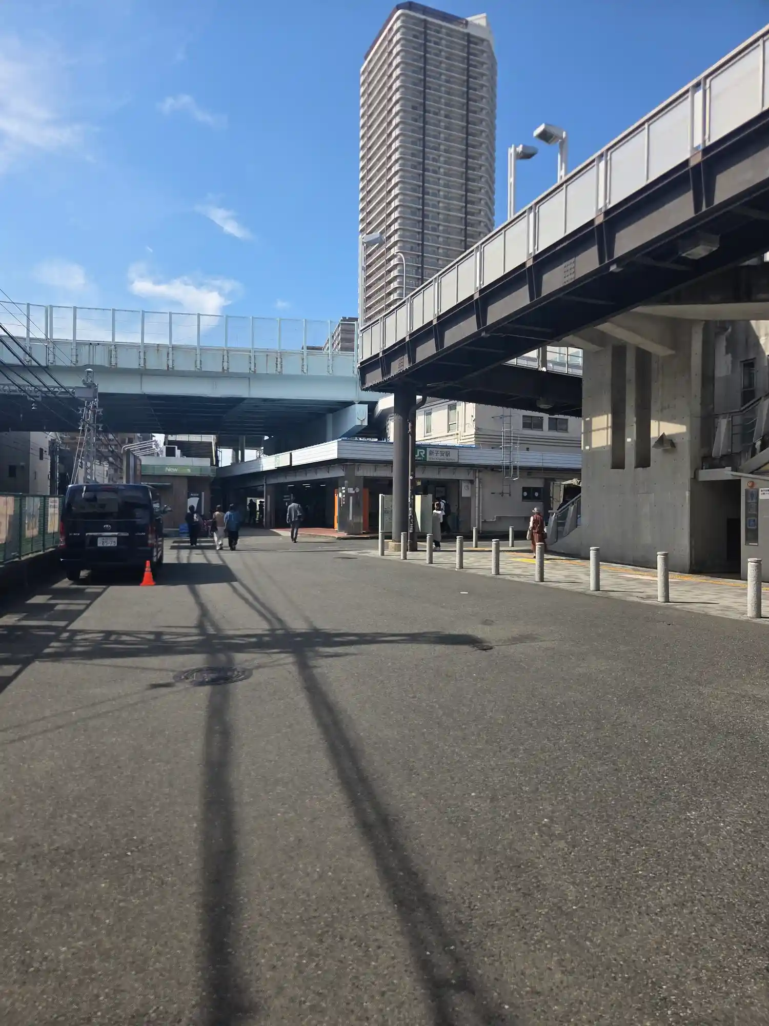 新子安駅(JR京浜東北線)の駅舎前の様子。背後には高層タワーマンションが建ち、頭上を歩道橋が通っている