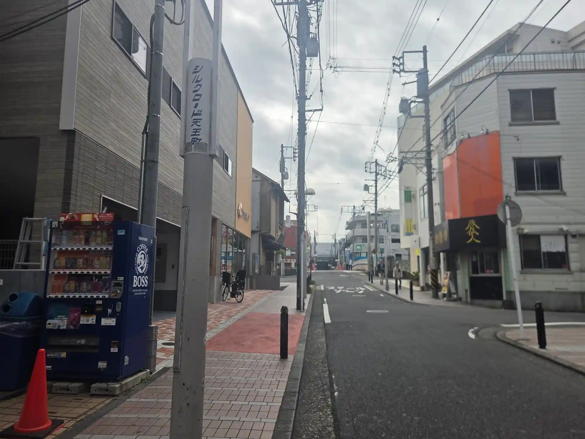 天王町駅周辺の「シルクロード天王町」の表示がある通り。歩道はカラー舗装で車道と分かれ、自動販売機や個人店が並ぶ