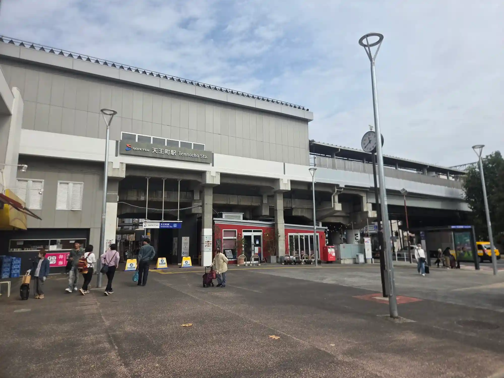 高架の上にある相鉄本線天王町駅の駅舎と駅前広場。高架下に店舗が入り、広場には時計とバス停がある