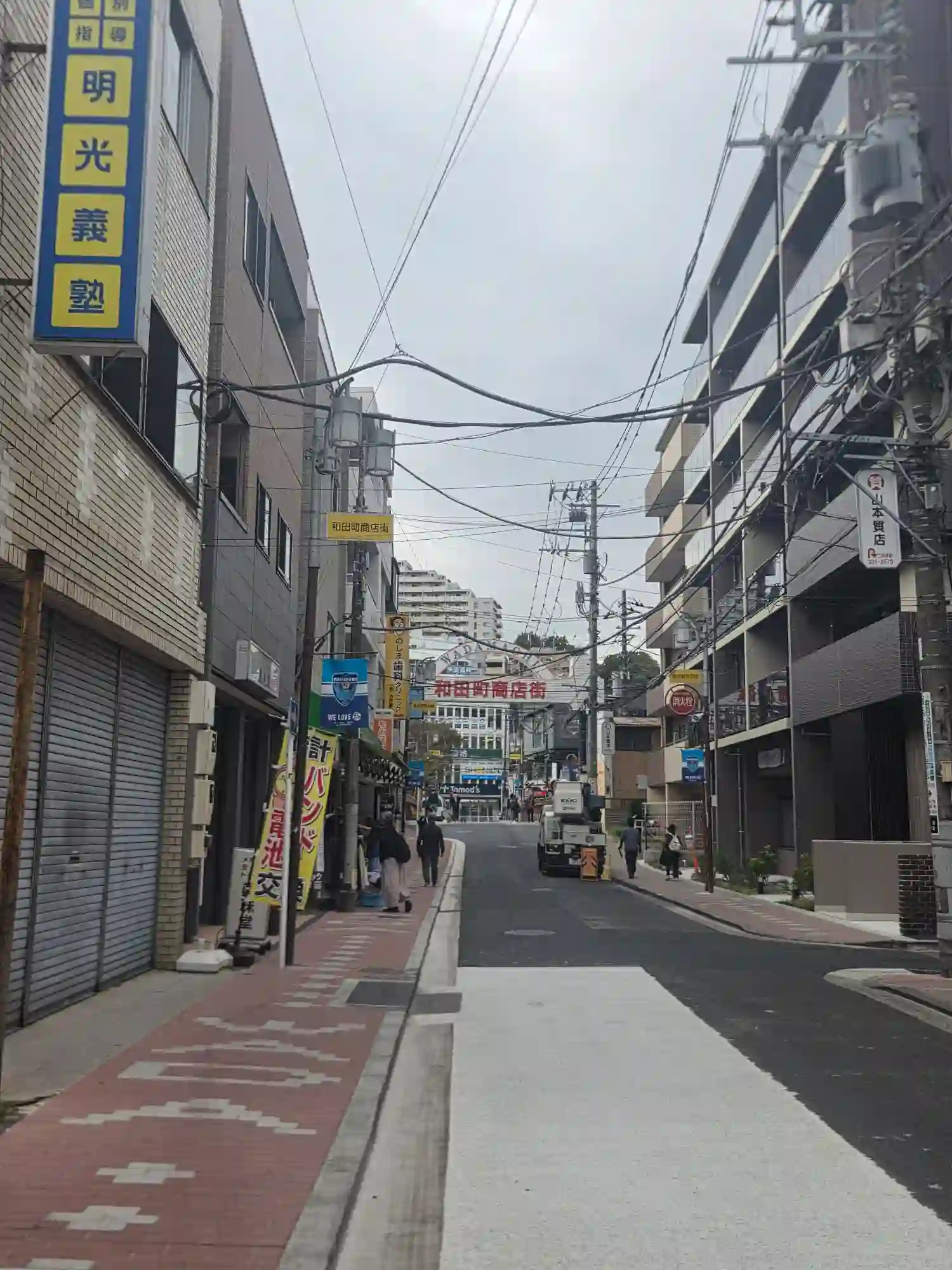 「和田町商店街」のアーチが見える通り。塾や歯科、時計店が並び、歩道が整備された生活感のある商店街